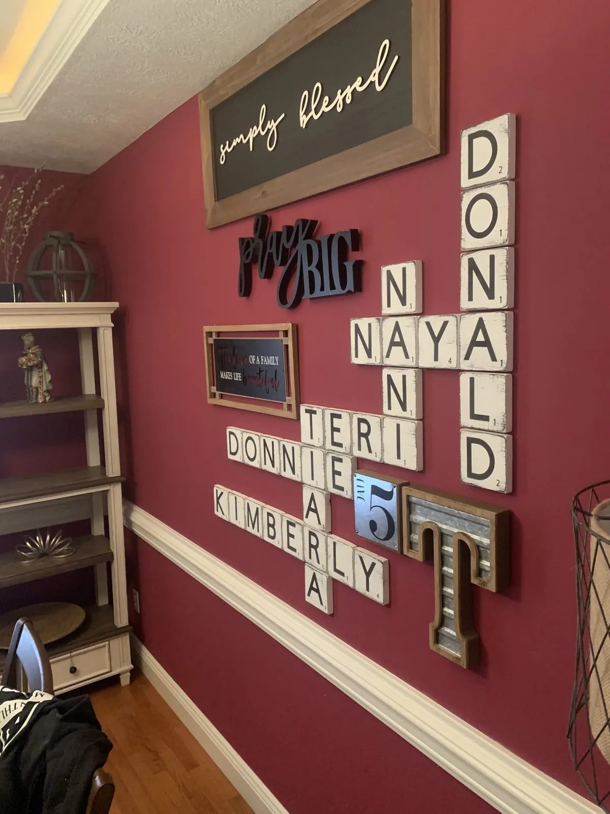 Dining room accent wall with white letter tiles spelling family names and a simply blessed sign
