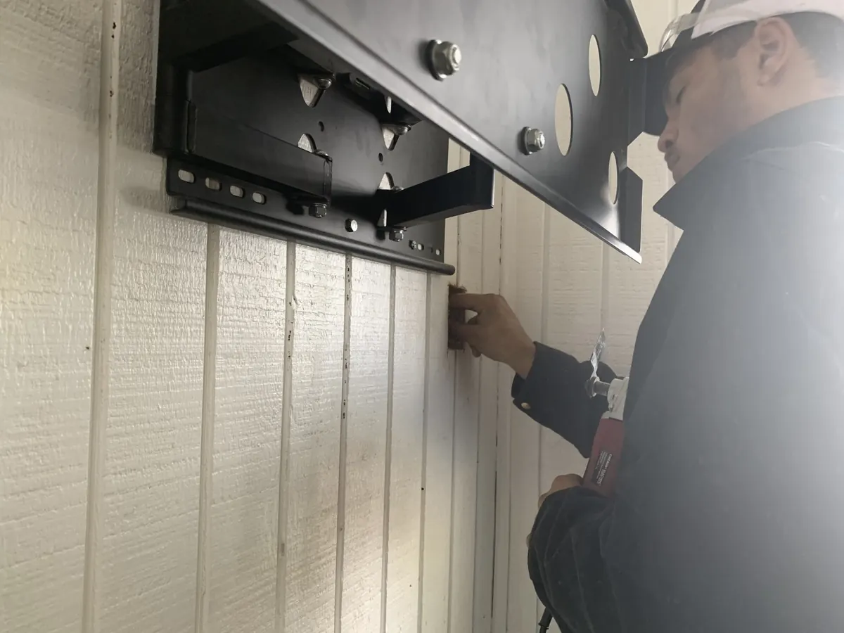 Worker mounting a black metal bracket to white siding by Monthly Upkeep in the Cleveland area